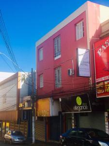 un edificio rojo con un coche aparcado delante de él en BALSAMO HOTEL, en Marília
