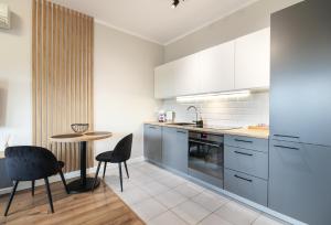 a kitchen with white cabinets and a table and chairs at Apartament Warta Park Poznań - Basen - Sauna - Klimatyzacja - Parking - Pelikan - - 24h check in in Poznań