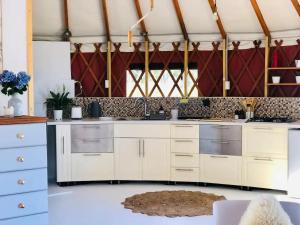 a kitchen with white cabinets and a sink at Byron Bay Hinterland Eco-Retreat Terracota Yurt in Eureka