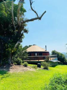 een groot gebouw met een rieten dak en een boom bij Byron Bay Hinterland Eco-Retreat Terracota Yurt in Eureka