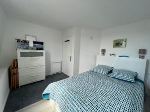 een slaapkamer met een bed met een blauw en wit dekbed bij Le Cocooning T2 rénové et 5min à pied de la mer au cœur de Trouville in Trouville-sur-Mer