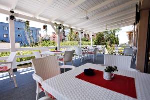 a patio with white tables and white chairs at Hotel Comfort in Shëngjin