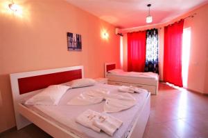 una camera con due letti e tende rosse di Hotel Comfort a Shëngjin
