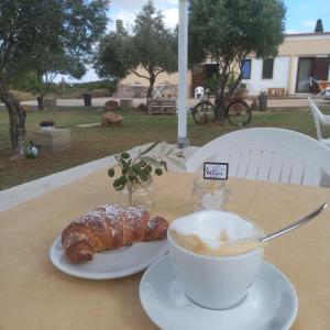 eine Tasse Kaffee und ein Croissant auf dem Tisch in der Unterkunft B&B GLI ULIVI in SantʼAnna Arresi