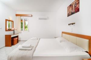 a white bedroom with a large bed and a window at Apollonio in Chrysi Ammoudia
