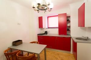 シビウにあるMedieval Central Apartment Sibiuのキッチン(赤いキャビネット、テーブル、シンク付)