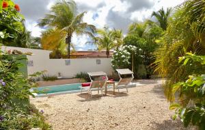 un patio con sillas, una mesa y una piscina en Apartment GreenFlash, en Kralendijk