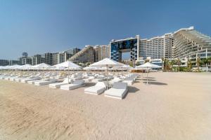 eine Reihe von weißen Stühlen und Sonnenschirmen am Strand in der Unterkunft FIVE Palm Resort - Luxury 2BR - Sea View in Dubai