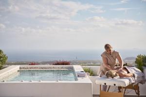 a woman standing on a chair next to a swimming pool at Alleys All-Suite Hotel & Spa in Pirgos
