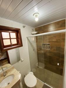 uma casa de banho com um chuveiro, um WC e um lavatório. em Chalés Raios de Sol em Monte Verde