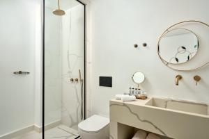 a bathroom with a sink and a toilet and a mirror at Alleys All-Suite Hotel & Spa in Pirgos