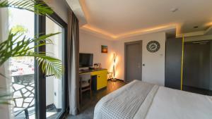 a bedroom with a bed and a desk and a clock at Sea Palm Otel Yalıkavak in Yalıkavak