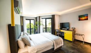 a bedroom with a bed and a desk with a television at Sea Palm Otel Yalıkavak in Yalıkavak
