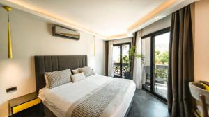 a bedroom with a large bed and a balcony at Sea Palm Otel Yalıkavak in Yalıkavak