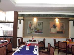 ein Esszimmer mit Tischen und Stühlen und Gemälden an der Wand in der Unterkunft Pedregal Palace in Mexiko-Stadt