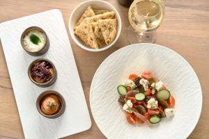 a table with two plates of food and a glass of wine at Alleys All-Suite Hotel & Spa in Pirgos