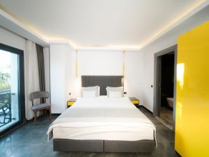 a bedroom with a large bed and a yellow wall at Sea Palm Otel Yalıkavak in Yalıkavak