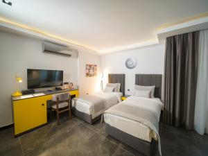 um quarto de hotel com duas camas e uma televisão em Sea Palm Otel Yalıkavak em Yalıkavak