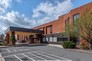 Best Western Plus Oswego Hotel and Conference Center في اوسويغو: موقف للسيارات أمام مبنى من الطوب
