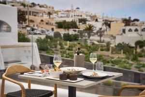 a table with wine glasses and food on a balcony at Alleys All-Suite Hotel & Spa in Pirgos