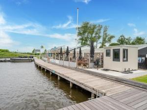 un quai avec un bâtiment et un bateau sur l'eau dans l'établissement Charming holiday home in Grou with fenced garden, à Grou