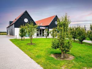 a black and white building with trees in front of it at Beautiful chalet in Oostkapelle with swimming pool in Oostkapelle