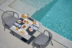 a table with plates of food next to a swimming pool at Alleys All-Suite Hotel & Spa in Pirgos