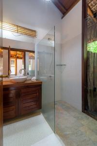 a bathroom with a glass shower and a sink at Villa Bulan in Arraial d'Ajuda