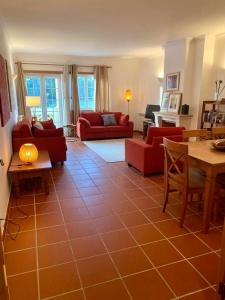 ein Wohnzimmer mit roten Möbeln und Fliesenboden in der Unterkunft Golf & Praia Del Rey - Óbidos -6 hospedes in Óbidos