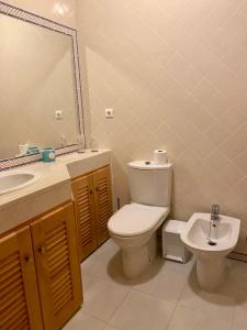 a bathroom with a toilet and a sink and a mirror at Golf & Praia Del Rey - Óbidos -6 hospedes in Óbidos