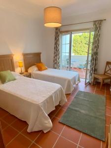 a bedroom with two beds and a balcony at Golf & Praia Del Rey - Óbidos -6 hospedes in Óbidos