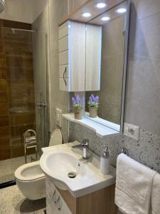 a bathroom with a sink and a toilet and a mirror at Costa Adriatica Apartments in Durrës