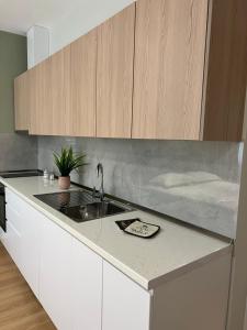 una cocina con armarios blancos y fregadero en Costa Adriatica Apartments, en Durrës