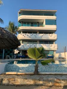 un hotel con una palmera frente a un edificio en Condominio Agave del Mar en Coyuca