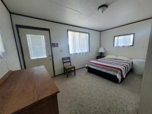 um quarto com uma cama, uma cadeira e uma mesa em Eagles Landing Campground em Sturgis