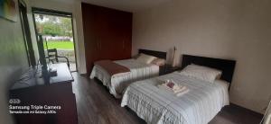 two beds in a hotel room with a window at La Casa del Lago in Otavalo