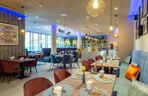 a restaurant with tables and chairs and a bar at Leonardo Hotel Augsburg in Augsburg
