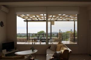 ein Wohnzimmer mit einem Sofa und einem großen Fenster in der Unterkunft Ένα σπίτι γεμάτο φύση! - A house full of nature! in Longá