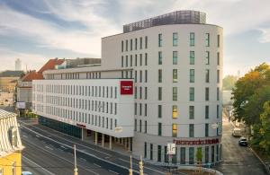 a tall white building on a city street at Leonardo Hotel Augsburg in Augsburg