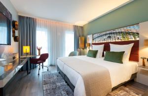 a hotel room with a large bed and a desk at Leonardo Hotel Augsburg in Augsburg +37 photos