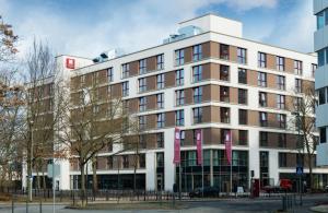 un grand bâtiment blanc avec des bannières roses sur lui dans l'établissement Leonardo Hotel Offenbach Frankfurt, à Offenbach-sur-le-Main