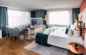 a bedroom with a bed and a desk with a television at Leonardo Hotel Zurich Airport in Kloten