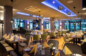 ein Esszimmer mit Tischen und Stühlen und Fenstern in der Unterkunft Leonardo Hotel Eschborn Frankfurt in Eschborn