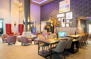 ein Restaurant mit Tischen, Stühlen und lila Wänden in der Unterkunft Leonardo Hotel Eschborn Frankfurt in Eschborn