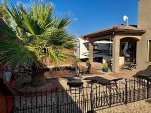 a fence in front of a house with a palm tree at Tiny RV Stone pool Inn, Pets stay free, Zion National Park, your private Oasis! in St. George