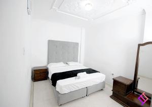 a white bedroom with a bed and a mirror at Apartamento Amoblado y Cómodo in Valledupar