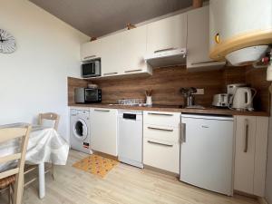 a kitchen with white cabinets and a washer and dryer at Appartement Urrugne, 2 pièces, 2 personnes - FR-1-239-508 in Urrugne