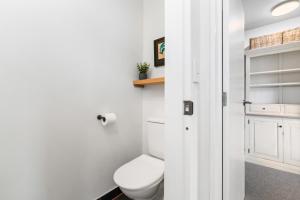 a white bathroom with a toilet and a shelf at Mountain View Bliss - Albert Town Holiday Unit in Albert Town