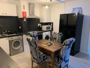 uma cozinha com uma mesa e cadeiras de madeira e um frigorífico em Lovely 5 Bedroom Home in Dagenham London em Goodmayes