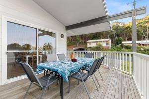 a table and chairs on a deck with a view of a porch at 24 Hyam Rd Hyams Beach in Hyams Beach
